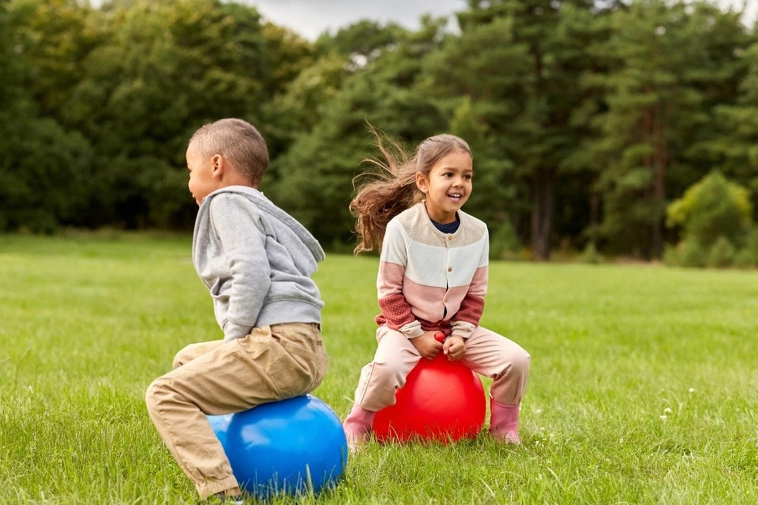 Two children bouncing on hopper balls during outdoor play